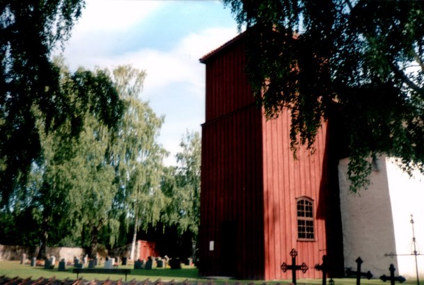 Romnes Kirke - tårnfot med deler av kirkegården på nordsiden - Tower with churchyard beyond.